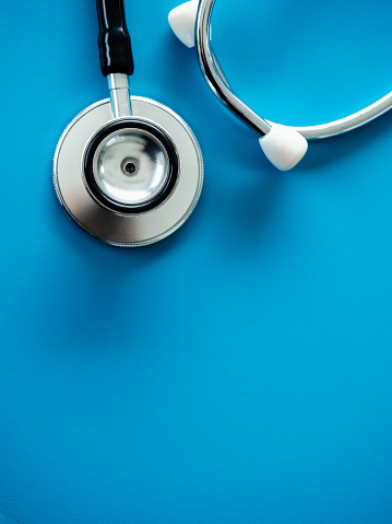 Close up stethoscope isolated on blue background with copy space, top view, vertical style. Healthcare and medical concept.
