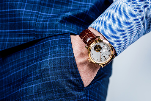 Analog wrist watch worn on male arm in trousers pocket, wristwatch.