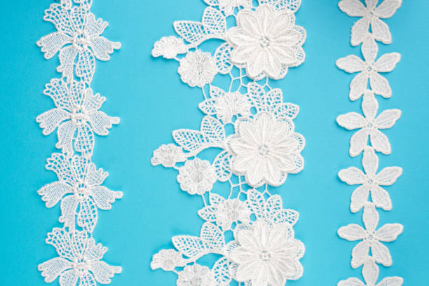 istock White laces with flowers and leaves on blue background isolated vertically 1413444121
