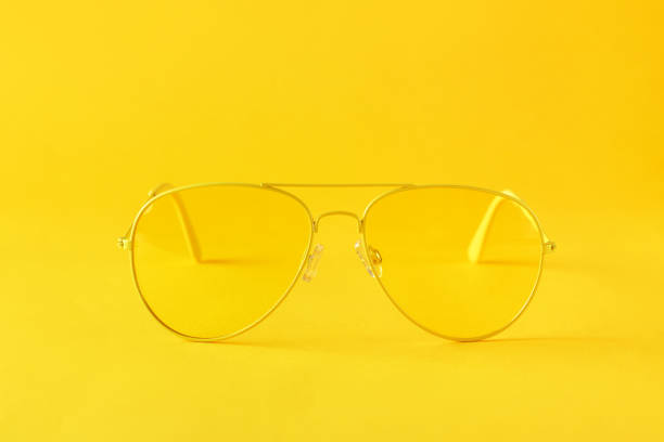 Modern yellow aviator sunglasses on yellow paper background. Summer or sun protection concept. Minimalism, monochrome, with space for text.