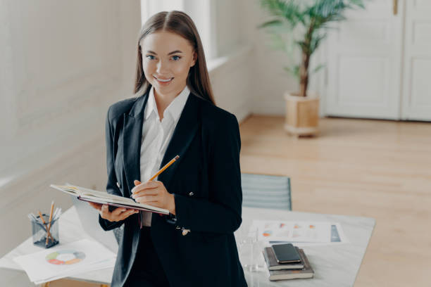 istock Smiling business woman making to do list while working at office 1413448005