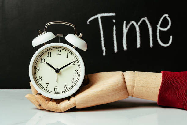 istock wooden hand holding alarm clock 1413449411