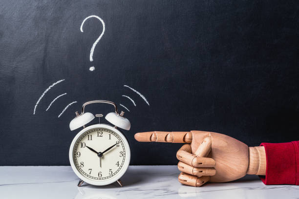 istock Hand reaches for an alarm clock with a question mark 1413449423