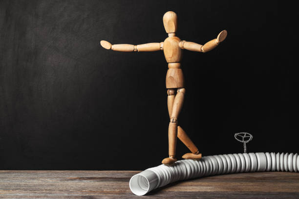 Wooden man balancing on a pipe stock photo