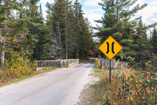 One lane bridge sign along a remote forest road on a sunny autumn day. Algonquin Park, ON, Canada.