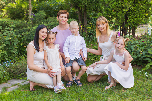 lifestyle shot of pregnant mother near her little daughters playing together and showing, stretching muscles.