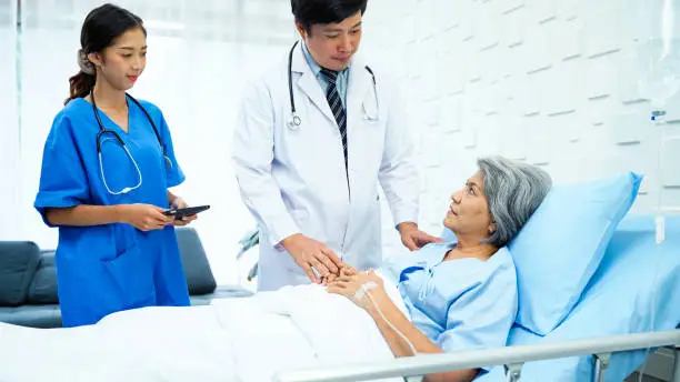 Photo of Specialist male doctor and his assistant came in to inquire about the symptoms of a female patient after receiving treatment.