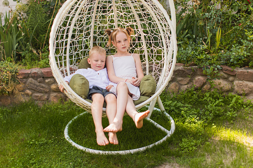 Blonde boy and girl on wicker lounge chair. Childhood. Summer vacation. Outdoor recreation. Rest. Children portrait together on sunbed. Leisure activity. Brother and sister. Friendship. Relationship