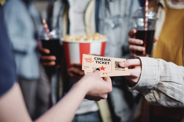 Unrecognizable people giving tickets for movie to cinema worker to enter hall, selective focus shot