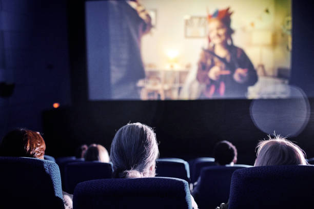 Watching Movie In Cinema Rear view shot of unrecognizable people spending spare time watching family movie on big screen at cinema film industry stock pictures, royalty-free photos & images