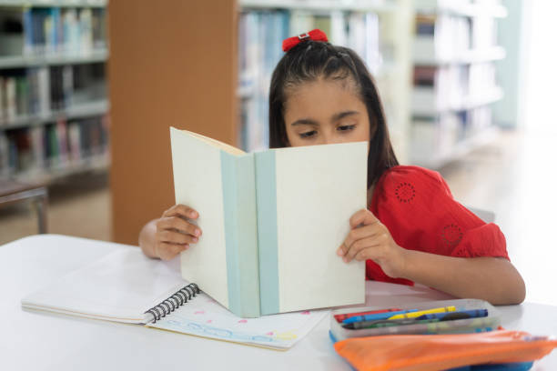 istock Girl with eyesight problem reading book close to eyes 1413453802