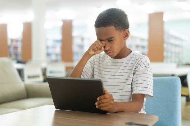 istock Little boy holding tablet and rubbing his eyes 1413456085