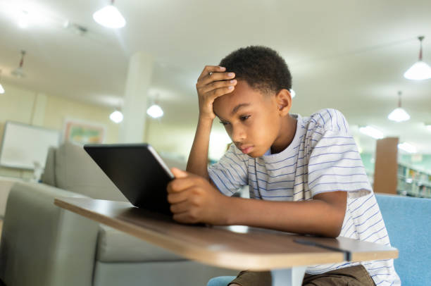 istock Nearsighted kid holding and looking at a tablet 1413456285