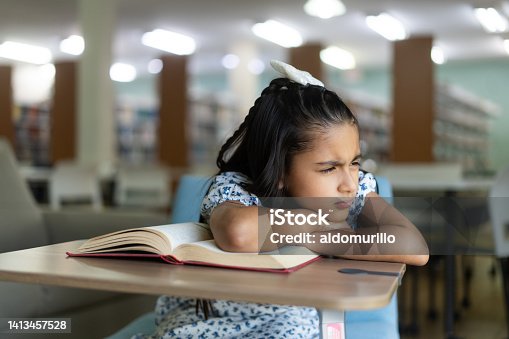 istock Little girl with book frowning away 1413457528