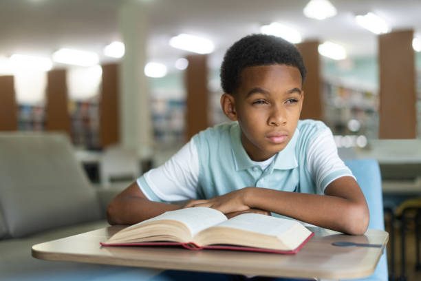 istock Boy sitting in class and trying to read board 1413457551