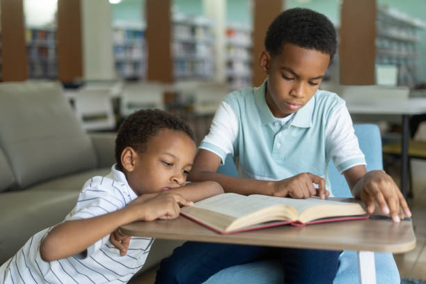istock Two boys reading book and following with finger 1413457553