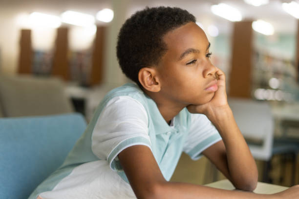 istock Little boy with head on hand looking away 1413457660