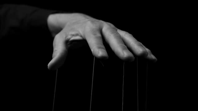 Man hand manipulating, controlling smth, moving fingers with strings. Master manipulation. Authority concept