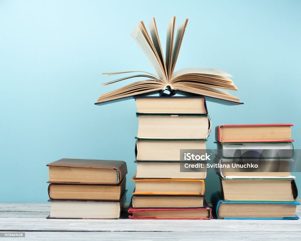 Open stacking book, hardback colorful books on wooden table and blue background. Back to school. Copy space for text. Education business concept. Open book, hardback colorful books on wooden table. Back to school. Copy space for text. Education business concept Back Stock Photo