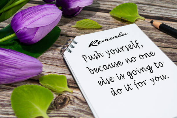istock Motivational quote on notepad with flowers on wooden desk. 1413463003