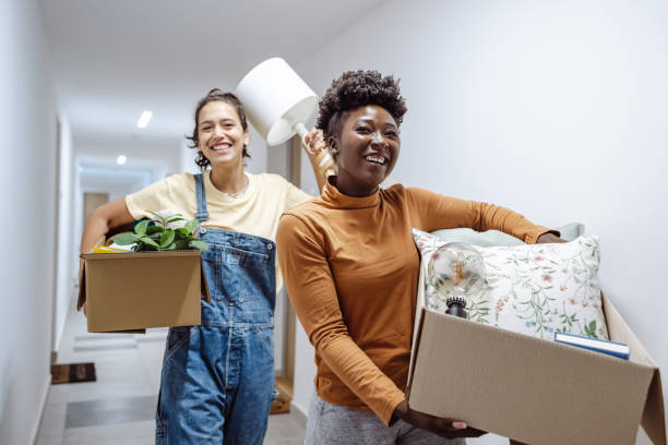 University students moving into campus accommodation Two female friends carrying cardboard boxes with belongings and moving into campus moving stock pictures, royalty-free photos & images