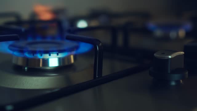 Three gas burners burn simultaneously on stove in dark. Circular gas-jet ignition