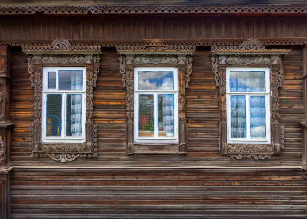 The beautiful old windows and roof with beautifully designed platbands window on an old wooden house in Semenov city. Nizhny Novgorod Region, Russia.