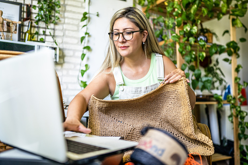 Adult woman taking online crochet lesson and making crochet bag