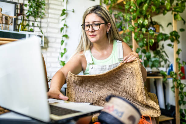 Adult woman taking online crochet lesson and making crochet bag stock photo
