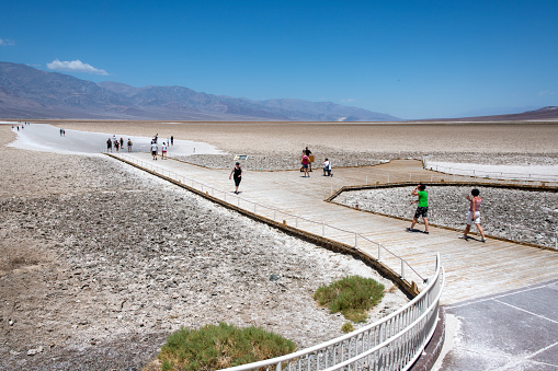 Badwater is located in Death Valley National Park. It is the lowest point in the United States at minus 282 feet below sea level. It is also the most visited attraction in the Park. Several tourists are visible exploring the site.\nDeath Valley National Park, California, USA\n6/13/2022