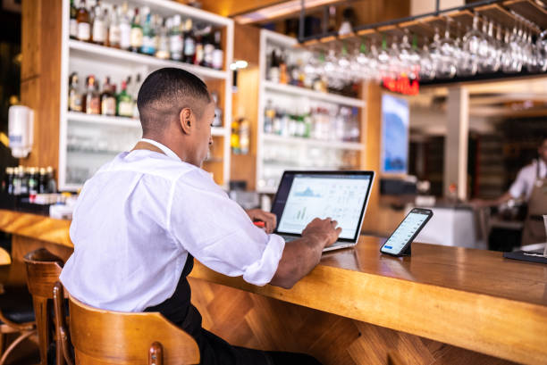 Waiter working on the laptop at a bar