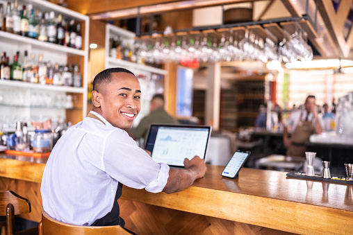 Portrait of a small business owner working using laptop at a bar