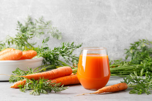 Carrot juice in a glass and fresh carrots with leaves Carrot juice in a glass and fresh carrots with leaves carrot juice stock pictures, royalty-free photos & images