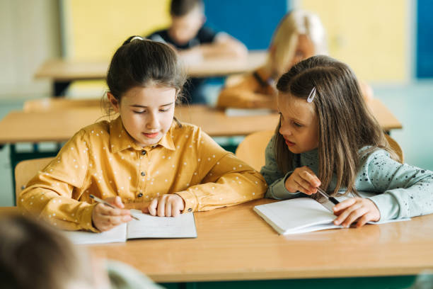 istock Two schoolgirls studying together in elementary school classroom 1413476290