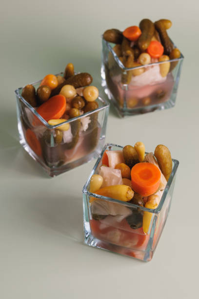 Istanbul, Turkey-August 7, 2022: Various pickles in three square glass bowls on a mint green background. Pickle bowls have white cabbage, carrots, gherkins and small peppers. Shot with Canon EOS R5.