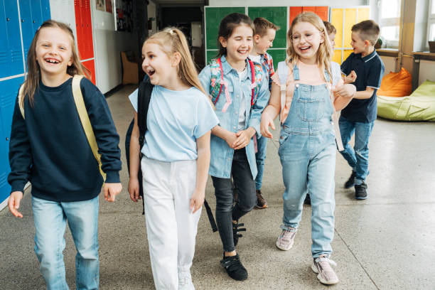 istock Smiling elementary students walking togetherness in corridor after school 1413479081