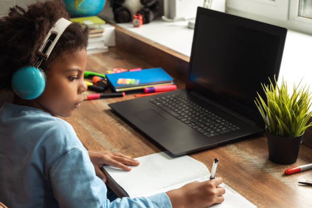 istock African-American girl doing homework,making notes,using headphones and laptop at home.Back to school concept.School distance education at home,home schooling,e-learning,diverse people 1413479217