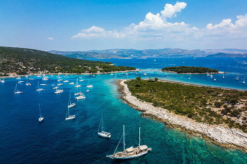 Magnificent bays of the Blue Lagoon in Dalmatia, Croatia, with amazing emerald-blue water and numerous boats seen from above and captured with a drone during one busy summer day on the Adriatic Sea.