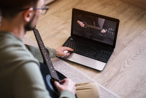 istock young man playing guitar at home by video lessons 1413480317