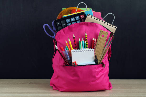 istock Pink backpack and school supplies on a black. 1413480330