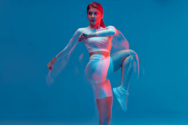 istock Fitness girl rasing hips, doing warm up exercise for legs on blue backdrop. Long exposure, motion blur. Sports workout 1413484210