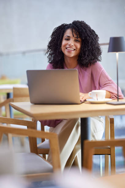 istock A happy multicultural journalist sits in a coffee shop and typing on a laptop while smiling at the camera. 1413487554