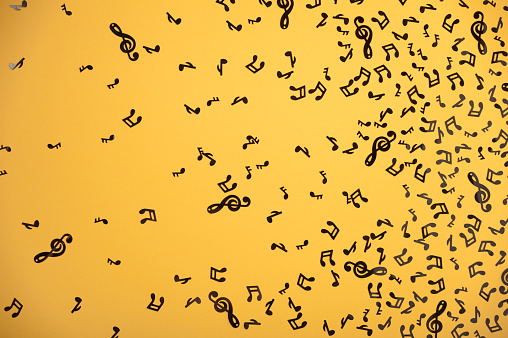 black plastic musical notes scattered on a yellow background