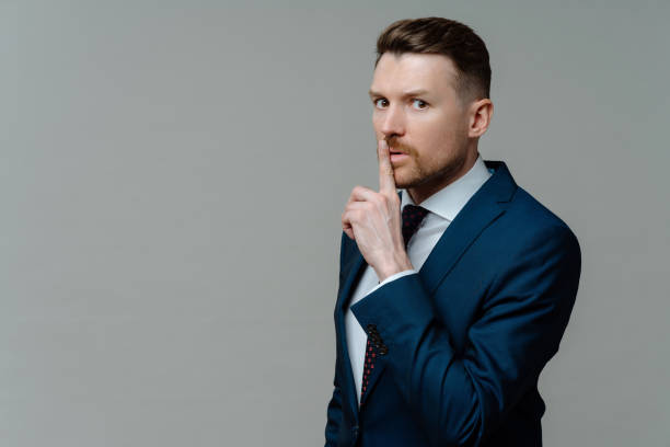 istock Young businessman in suit asking to keep information in secret 1413493829