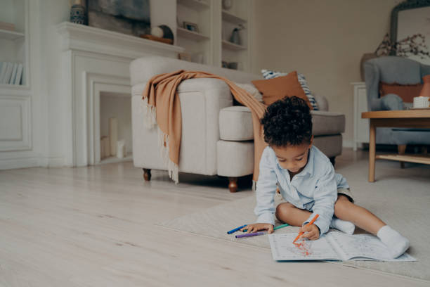 istock Little mixed race kid boy drawing in coloring book while spending leisure time alone at home 1413494664