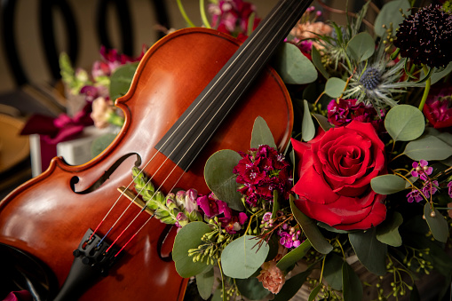 Close up of a Violin surrounded by a bouquet of flowers including roses