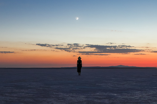 A woman and the crescent moon in the salt lake