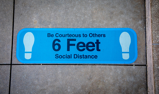 COVID related floor sign requesting maintaining six feet of distance