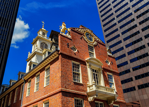 Boston, Massachusetts, USA - August 2, 2022: Skyward view of the Old State House building between modern skyscrapers . Built in 1713, it is one of the landmarks on Boston's Freedom Trail.