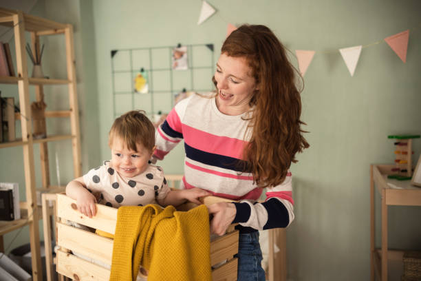 istock Young woman holding a box with her cute baby inside 1413505965